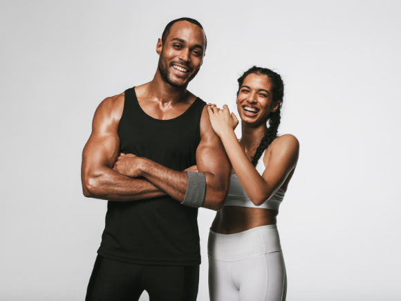 Two diverse individuals in stylish workout gear stand in an exclusive Los Angeles body transformation studio that offers upscale fitness for busy men and women.