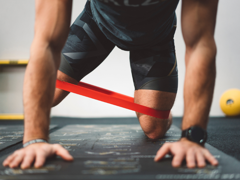 A young man performs quadruped mini-band exercises as a part of a corrective exercise program in Los Angeles.