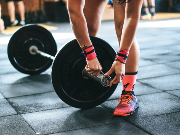 A female sets up a barbell for a deadlift exercise as a part of a strength training program.
