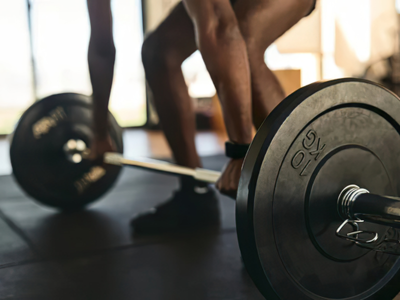 A man performs a barbell deadlift as a part of a progressive strength training program in a private training studio